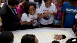 FILE - Michele de Oliveira grieves over the coffin containing her 13-year-old son, Paulo Henrique Oliveira, in Rio de Janeiro, Brazil, April 26, 2017. Paulo lived with his family in the Alemao complex of slums and was walking to visit a neighbor when he w