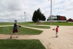 FILE - Jeremiah Bronson, of Ames, Iowa, plays catch with his son Ben on the field at the 'Field of Dreams' movie site, June 5, 2020, in Dyersville, Iowa.