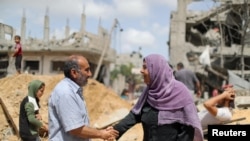 Un hombre y una mujer palestinos se saludan entre escombros en la Franja de Gaza el 21 de mayo de 2021, después de la tregua acordada entre Israel y Gaza.