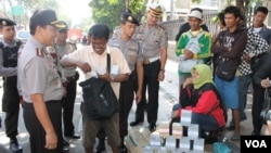 Pemeriksaan dan peringatan penukaran uang di pinggir jalan Surabaya untuk menghindari perdagangan uang palsu. (VOA/Petrus Riski)