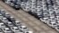 FILE - A man walks among cars which are ready for export at the port of Taipei, northern Taiwan, April 16, 2014. 