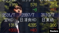 A pedestrian is reflected on a stock quotation board showing stock prices outside a brokerage in Tokyo May 8, 2013. 