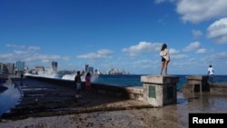 Sejumlah turis tampak mengambil gambar di pinggir laut Malecon, Havana, Kuba, pada 13 Februari 2023. (Foto: Reuters/Alexandre Meneghini)