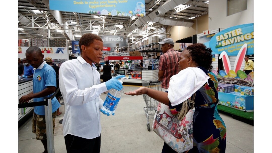 A store assistant gives people hand sanitizer as shoppers stock up on groceries at a Makro Store ahead of a nationwide 21-day lockdown in an attempt to contain the coronavirus disease outbreak in Durban, South Africa, March 24, 2020.