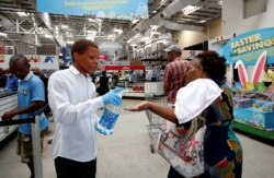 A store assistant gives people hand sanitizer as shoppers stock up on groceries at a Makro Store ahead of a nationwide 21-day lockdown in an attempt to contain the coronavirus disease outbreak in Durban, South Africa, March 24, 2020.