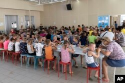 Children from different orphanages from the Donetsk region eat a meal at a camp in Zolotaya Kosa, southwestern Russia, Friday, July 8, 2022. (AP Photo)