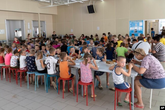 Children from different orphanages from the Donetsk region eat a meal at a camp in Zolotaya Kosa, southwestern Russia, Friday, July 8, 2022. (AP Photo)