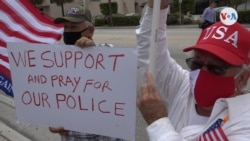 Dos manifestantes posan junto a un cartel con el mensaje "Nosotros apoyamos y rezamos por nuestra policía" durante una marcha en Miami.[Foto: Antoni Belchi,VOA]