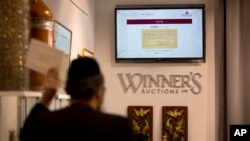 FILE - An ultra Orthodox Jewish man, center, bids during an auction in Jerusalem, March 6, 2018 for a handwritten note by Nobel-winning scientist Albert Einstein.