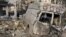 Residents walk past a damaged emergency vehicle in Aleppo, Syria, January 1, 2013.
