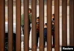 FILE - Migrants are detained by a U.S. Border Patrol agent after crossing the Rio Bravo to turn themselves in to request asylum in El Paso, Texas, as seen from Ciudad Juarez, Mexico, March 29, 2021.