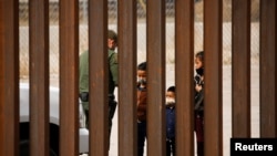 FILE - Migrants are detained by a U.S. Border Patrol agent after crossing the Rio Bravo River to turn themselves in to request asylum in El Paso, Texas, as seen from Ciudad Juarez, Mexico, March 29, 2021. 