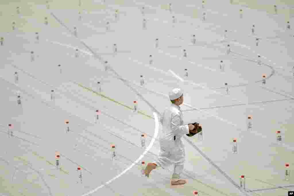 Seorang anak laki-laki berlari di antara botol-botol yang diletakkan di lantai gedung olahraga sebelum salat Ied di Bucharest, Rumania, 4 Juni 2019. (Foto: AP)