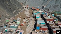 Residentes camina sobre una calle cubierta de escombros debido a un alud, en Camaná, Perú, el 7 de febrero de 2023. 