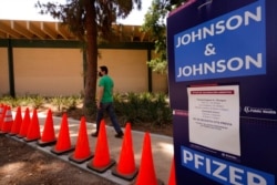 FILE - A man arrives for his appointment to get vaccinated, as banners advertise the availability of the Johnson &amp; Johnson and Pfizer COVID-19 vaccines at a county-run vaccination site at the Eugene A. Obregon Park in Los Angeles, July 22, 2021.