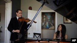 Musisi David Shenton dan Erin Shields tampil virtual dari rumah mereka di wilayah Queens, New York, 30 Maret 2021. (AP Photo/Emily Leshner)