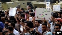 Unemployed Tunisian graduates hold signs as they shout slogans during a demonstration in Tunis to demand jobs and call for the resignation of the ruling government, September 29, 2012.