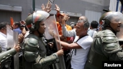 Supporters of jailed opposition leader Leopoldo Lopez shout to supporters of Venezuela's President Nicolas Maduro as Venezuelan National Guardsmen try to control the crowd outside the courthouse during his trial in Caracas, Sept. 10, 2015.