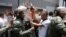 Supporters of jailed opposition leader Leopoldo Lopez shout to supporters of Venezuela's President Nicolas Maduro as Venezuelan National Guardsmen try to control the crowd outside the courthouse during his trial in Caracas, Sept. 10, 2015.