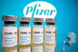 Los frascos con una etiqueta que dice "COVID-19 y una jeringa médica se ven frente al logotipo de Pfizer, 31 de octubre de 2020.