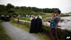 FILE- In this June 13, 2014, file photo "Game of Thrones" fans stop for a picture on their way to Audleys field and castle,in Northern Ireland. 