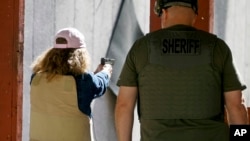 In this Saturday, June 29, 2019, photo, Cindy Bullock, Timpanogos Academy secretary, participates in shooting drills at the Utah County Sheriff's Office shooting range during the teacher's academy training, in Spanish Fork Canyon, Utah.