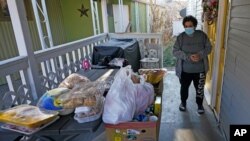 Evelyn Maysonet looks at the food delivery from the Weber-Morgan Health Department, Nov. 24, 2020, in Ogden, Utah. Maysonet has been isolating with her husband and son in their Ogden home since all three tested positive for COVID-19 over a week ago.