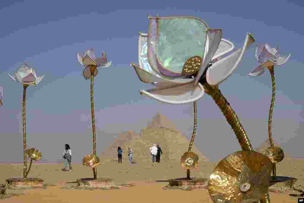 Visitors walk past the &quot;Padma/Pulse and Bloom&quot; art installation of Indian artist Shilo Shiv Suleman during the &quot;Forever Is Now&quot; contemporary art exhibition at the historical site of the Giza Pyramids, on the outskirts of Cairo, Egypt.