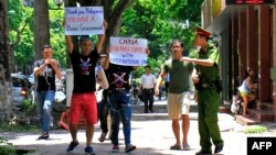 A policeman, right, reacts as demonstrating activists hold anti-China banners in Hanoi, July 17, 2016. 