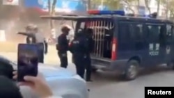 Security officers stand near a police vehicle following an explosion after artillery shells fell in Nansan, Yunnan Province, China, in this screengrab obtained from a social media video, released on Jan. 3, 2024.