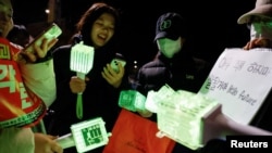 FILE - Fans of K-pop boy band NCT sing one of their songs while holding light sticks, as they attend a protest rally calling for the impeachment of South Korean President Yoon Suk Yeol, near the National Assembly in Seoul, South Korea, December 8, 2024.