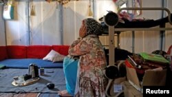 FILE - Syrian refugee Walaa, 26, sits inside her family's tent at the Souda municipality-run camp on the island of Chios, Greece, Sept. 7, 2016. 