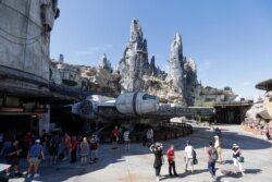 Park visitors walk near the entrance to the Millennium Falcon Smugglers Run ride during a preview of the Star Wars themed land, Galaxy's Edge in Hollywood Studios at Disney World, Aug. 27, 2019, in Lake Buena Vista, Florida.