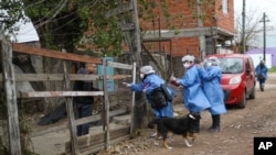 Trabajadores sanitarios entrevistan a un residente fuera de su casa en el barrio de Villa Azul, aislado en cuarentena después de que más de 50 residentes dieron positivo del nuevo coronavirus en las afueras de Buenos Aires, Argentina.