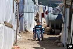 FILE - A disabled Syrian refugee boy sits in his wheelchair in a refugee camp in the town of Bar Elias, in Lebanon's Bekaa Valley, April 23, 2018.