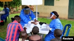 Para petugas kesehatan Uganda berbicara kepada warga sebelum melaksanakan latihan vaksinasi Ebola di Desa Kirembo, di Distrik Kasese, Uganda dekat perbatasan Republik Demokratik Kongo, 16 Juni 2019. 