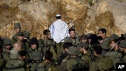 An Israeli soldier covered in a prayer shawl prays as Israeli troops gather near the border fence between Israel and Syria near the village of Majdal Shams in the Golan Heights, May 16, 2011