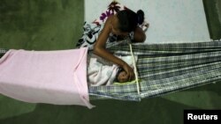 Miriam Araujo, 25, caresses Lucas, her 4-month-old child born with microcephaly as he sleeps on a hammock inside their house, in Sao Jose dos Cordeiros, Brazil, Feb. 16, 2016.