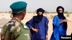 A Malian soldier speaks with Tuareg men Seydou (C) and Abdoul Hassan in the village of Tashek, outside Timbuktu, July 27, 2013. 