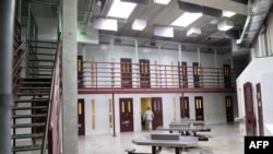 FILE - This photo made during an escorted visit and reviewed by the US military shows an US Army soldier walking at unused common detainee space in "Camp 6" detention facility at the U.S. Naval Station in Guantanamo Bay, Cuba, April 8, 2014.