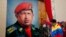 Venezuelan Vice President Nicolas Maduro raises his fist next to a painting of President Hugo Chavez during the commemoration of the 21st anniversary of Chavez's attempted coup d'etat in Caracas February 4, 2013. 