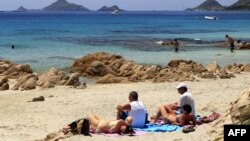 People sit on the Terre Sacree beach in Ajaccio on June 25, 2016 on the French island of Corsica.