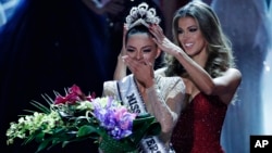 Former Miss Universe Iris Mittenaere, right, crowns new Miss Universe Demi-Leigh Nel-Peters at the Miss Universe pageant, Nov. 26, 2017, in Las Vegas. 