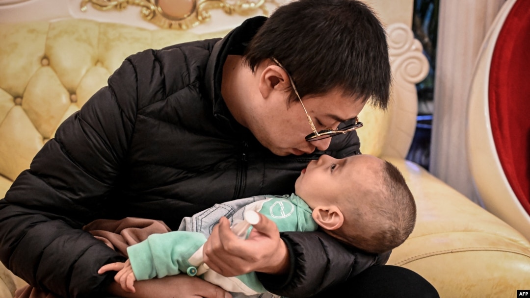 La foto tomada el 21 de octubre de 2021 muestra a Xu Wei sosteniendo a su hijo Xu Haoyang, diagnosticado con síndrome de Menkes, después de extraer orina de su vejiga para analizarla en un hospital, en su casa en Kunming, en la provincia de Yunnan, suroeste de China.
