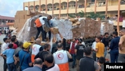 Para anggota organisasi Bulan Sabit Merah Palestina membagikan bantuan kepada para warga di Deir al-Balah, Jalur Gaza, pada 25 Oktober 2023. (Foto: Palestine Red Crescent Society/Handout via Reuters)