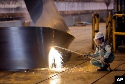 In this photo taken on May 31, 2012, an Iranian worker cuts a steel roll at the Mobarakeh Steel Complex located south of the capital Tehran.