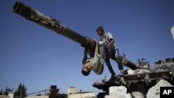 A boy looks back while he and another boy play on a Syrian military tank, destroyed during fighting with the Rebels, in the Syrian town of Azaz, on the outskirts of Aleppo, Sunday, Sept. 2, 2012.