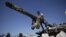 A boy looks back while he and another boy play on a Syrian military tank, destroyed during fighting with the Rebels, in the Syrian town of Azaz, on the outskirts of Aleppo, Sunday, Sept. 2, 2012.