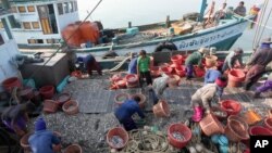 Migrant workers work on fishing boats at a pier in Prachuabkhirikhant province, southern Thailand Tuesday, March 4, 2014. An environmental and human rights group charged Tuesday that Thailand is not adequately addressing severe abuse against migrant workers in the Thai fishing industry. (AP Photo/Apichart Weerawong)