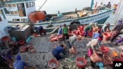 Migrant workers work on fishing boats at a pier in Prachuabkhirikhant province, southern Thailand Tuesday, March 4, 2014.